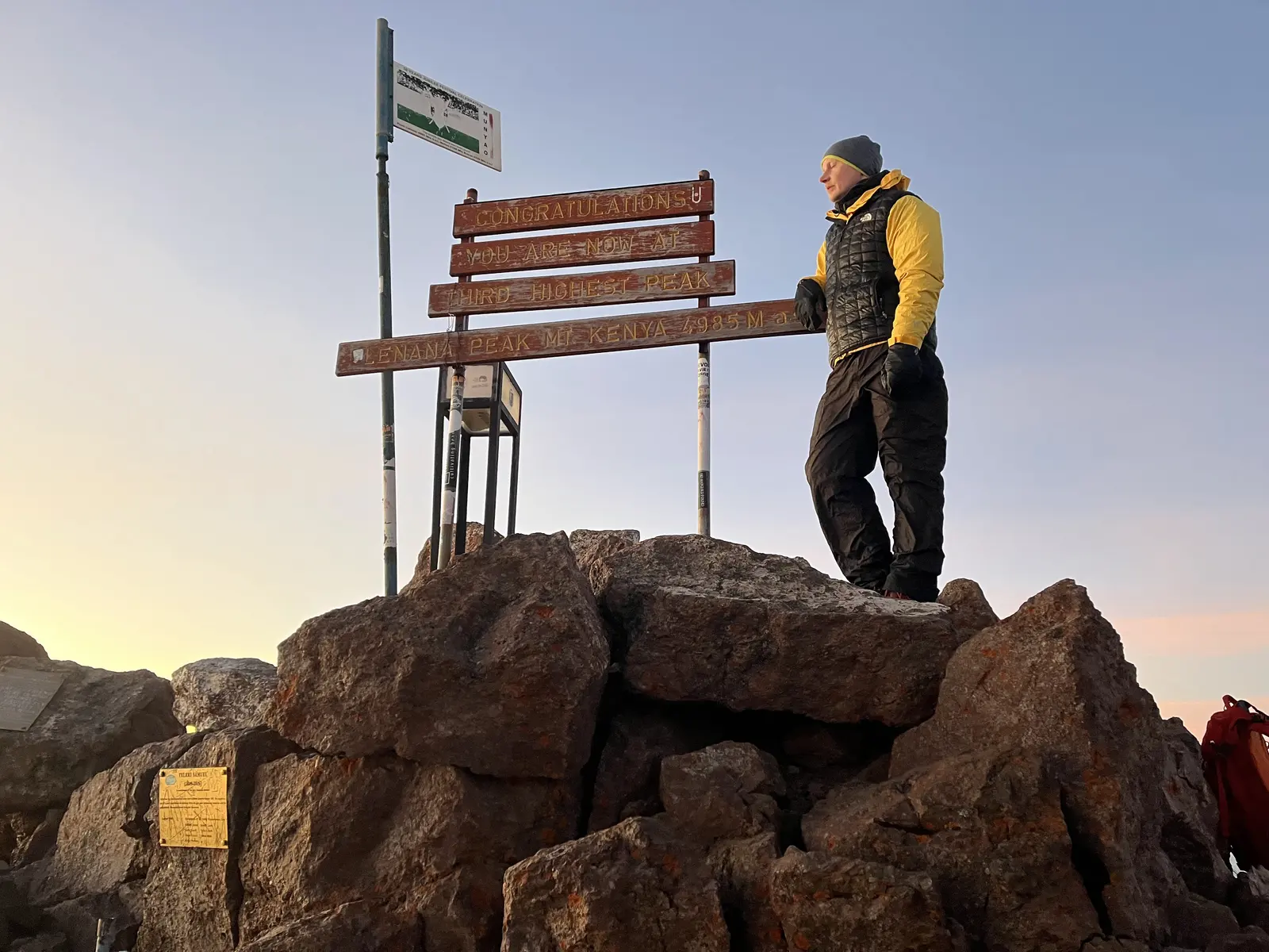 Hikers at the Point Lenana summit sign on Mount Kenya
