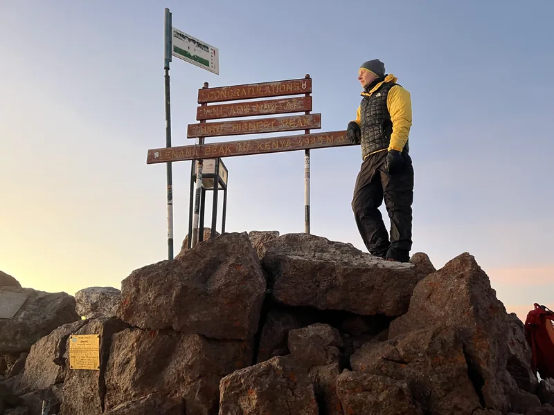 Hikers at the Point Lenana summit sign on Mount Kenya