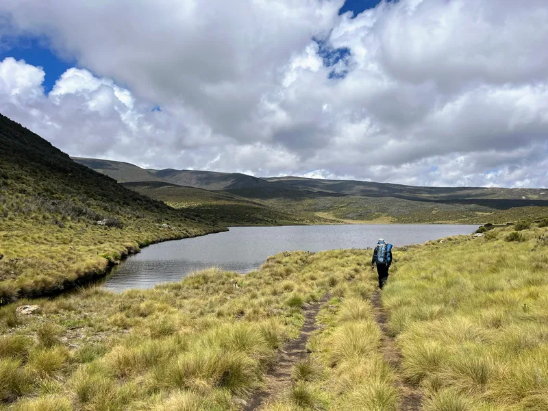A hiker beside a lake on Mount Kenya