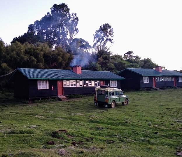 accommodation huts on Mount Kenya with an off-road vehicle parked outside. 