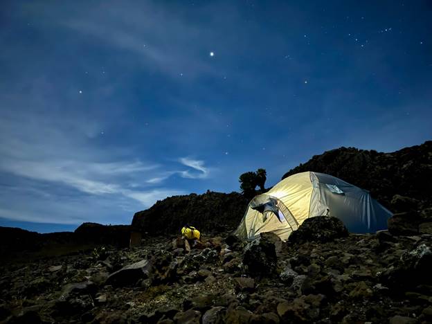 A tent set up in the alpine landscape of Mount Kenya with at dusk with stars appearing. 