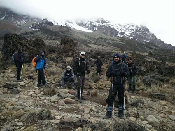 Tour guides and Italian tourists at near Mount Kilimanjaro summit in full mountaineer gear.